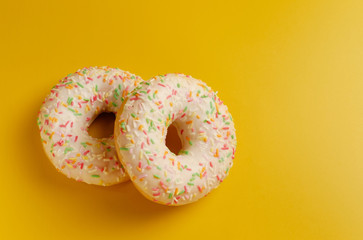 two white donuts on yellow background top view copy space