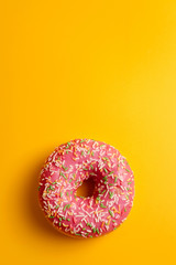 pink donut on yellow background top view copy space