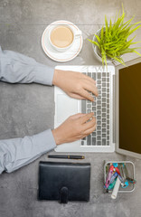 Top view of businessman working using laptop with coffee, potted plant, notebook and business accessories