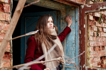 Girl in a red coat in an abandoned old building in late autumn