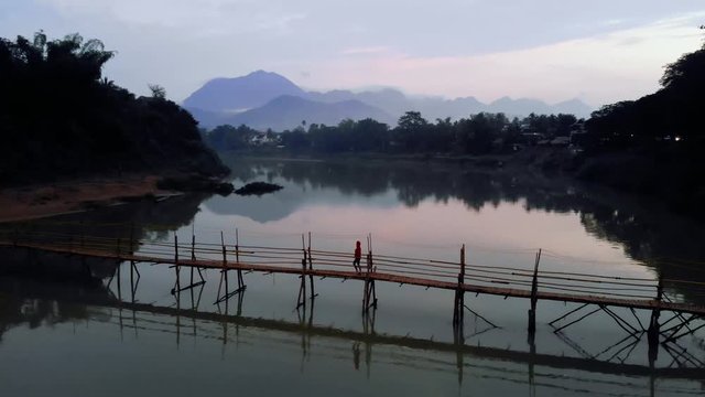 young Girl tourist walks on the bridge of bamboo across the Nam Kahn River in city Luang Prabang. Laos. quadcopter, flying, movement, motion, 4K move drone