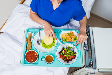 Tray with breakfast for the young female patient. The young woman eating in the hospital.