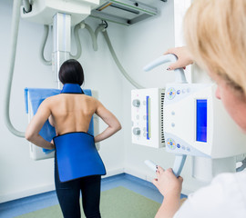 Radiologist and patient in a x-ray room. Classic ceiling-mounted x-ray system.