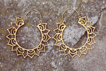 Brass metal earrings on rocky background