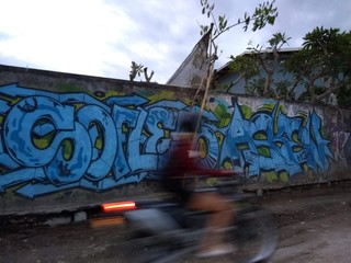 motorbiker in bali in front of graffiti wall 