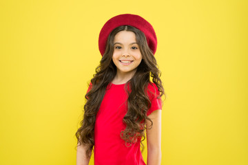 parisian child on yellow background. little girl in french style hat. childhood. hairdresser salon. summer fashion and beauty. happy girl with long curly hair in beret. parisian girl looks gorgeous