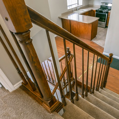 Square Staircase inside a house overlooking the kitchen and an empty room