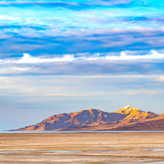 Square Vast sandy shore of a lake under bright blue sky with thick puffy clouds
