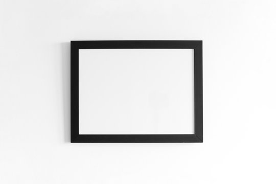 Black frame for paintings or photographs on the white wall. High resolution.