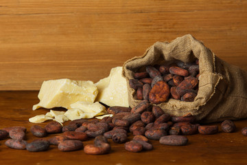 Cocoa beans and cacao butter on wooden background