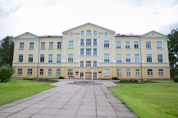 City Priekuli, Latvian Republic. Old manor where is school. Yellow house and sidewalk. Jun 1. 2019 Travel photo.