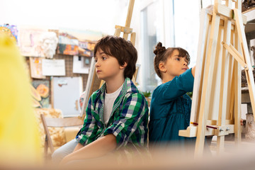 Obraz premium Dark-haired boy feeling bored during art lesson at school