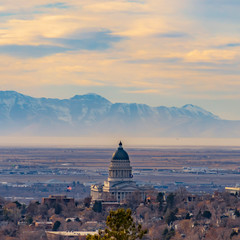 Obraz premium Square frame Panorama of downtown Salt Lake City against majestic mountain and cloudy sky