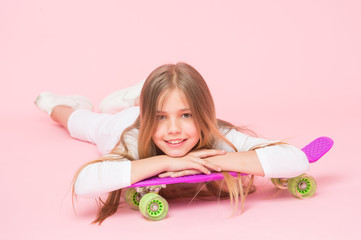 Obraz na płótnie Canvas Trendy girl. Ride penny board and do tricks. Girl likes to ride skateboard. Active lifestyle. Girl having fun with penny board pink background. Kid adorable child long hair adore ride penny board