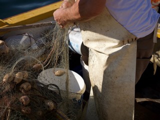 Fischfang noch nach guter alter Tradition, mit selbstgeknüpftem Netz, einem kleinen Fischerboot und jede Menge Ausbeute von heute Morgen, frischer Fisch aus der Adria