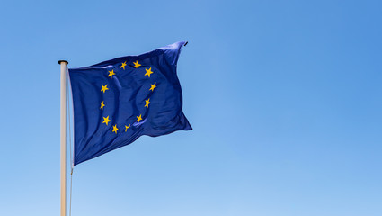 European Union Flag waving in the wind with a clear blue sky background - obrazy, fototapety, plakaty