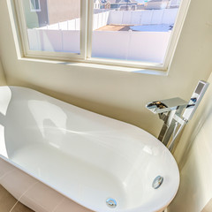 Square frame Bathroom interior with a gleaming bathtub against white wall and gray floor