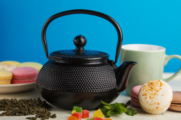 Tea ceremony. Cast iron kettle, tea, flowers, macaroons and sweets. Copy space.