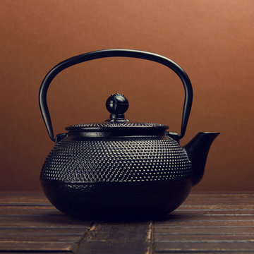 Cast iron black kettle on the table on a brown background. Tea ceremony.