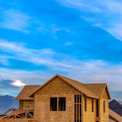 Square frame Exterior of a house under construction against vivid blue sky with clouds