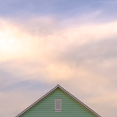 Square frame Top exterior of a house with view of the light green wall and gable vent
