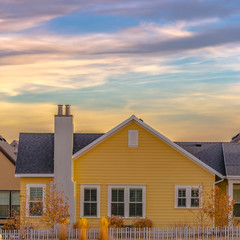 Square Exterior of a single storey home with yellow wall and dark gray roof