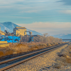 Square Railway track passing in front of a mining area viewed on a sunny day