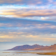 Square Panorama of a calm lake with vast sandy shore under cloud filled sky