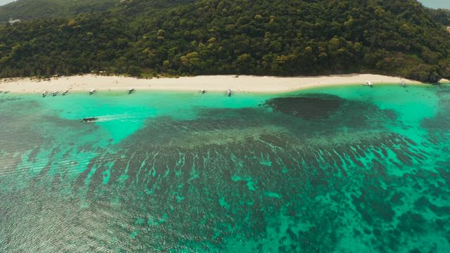 Tropical white sand beach, near the blue lagoon and corall reef from above, Boracay, Philippines. Sandy beach with tourists. Summer and travel vacation concept.
