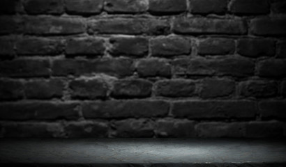 Old wood table with blurred concrete block wall in dark room background.