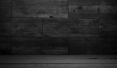 Old wood table with blurred concrete block wall in dark room background.