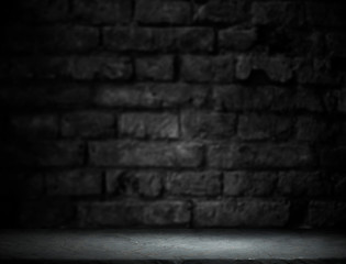 Old wood table with blurred concrete block wall in dark room background.