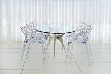 A large glass table with plastic chairs in the hotel's living room. Interior of the room of the villa.