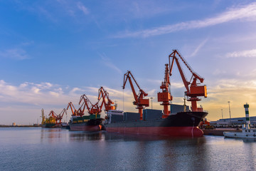 Obraz premium Heavy Loader Working in a Harbour in the Background of Sunset