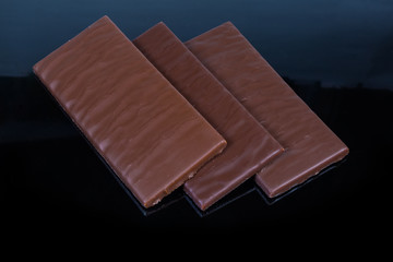 Bars of the milk chocolate on a dark background