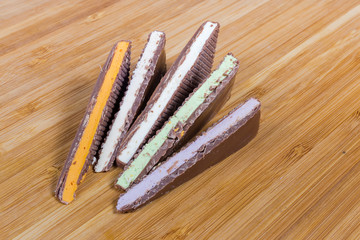 Slices of milk chocolate with varicolored filling on wooden surface