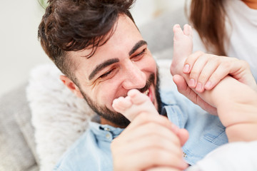 Vater hält beim Spielen die Füße von Baby