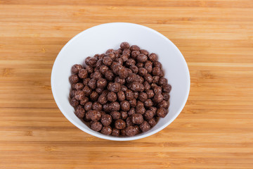 Breakfast cereal chocolate balls in bowl on a wooden surface