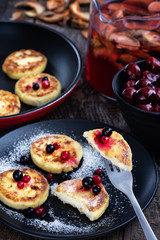 Cheese Pancakes with berries on a black plate.