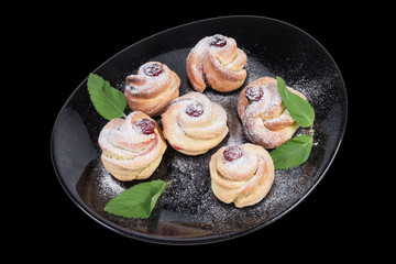 Baked sweet rolls and mint leaves on the black dish