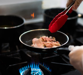 chef cooking in the kitchen, fresh fried bacon in a pan