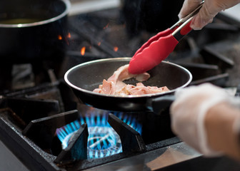 chef cooking in the kitchen, fresh fried bacon in a pan