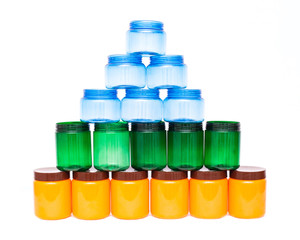 pyramid multicolored plastic jars of orange, green and blue on a white background, polyethylene terephthalate