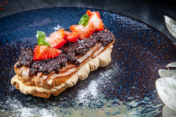 Traditional french eclairs served on premium dark plate. Food for breakfast with copy space. Close...