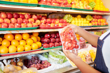 Fototapeta na wymiar Package of strawberries in hands of female grocery store customer
