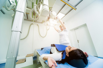 Radiologist and patient in a x-ray room. Classic ceiling-mounted x-ray system.