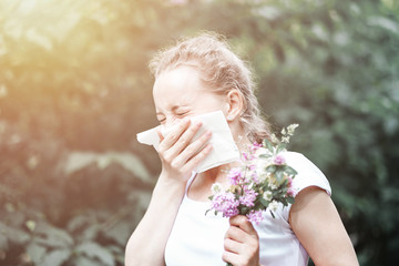 Pollen allergy, womansneezing with bouquet of flowers. Concept: seasonal allergy.