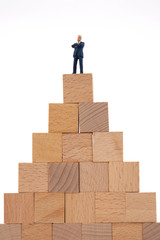 Miniature businessman standing on wooden block