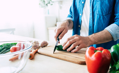 Man cooking healthy food. Fresh vegetables on the cutting board. Concept of cooking. Diet. Healthy and vegan lifestyle. Cooking at home. Prepare food. Male hands cutting vegetables in the kitchen