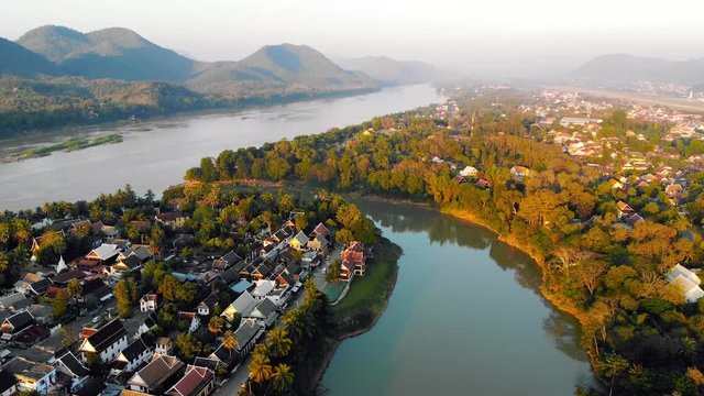Aerial view of Luang Prabang and surrounding lush mountains of Laos. The Nam Kahn River, a tributary of the Mekong River, flows peacefully on the right.